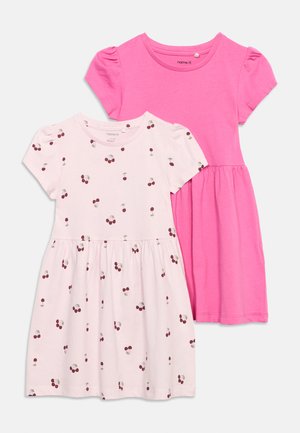 Deux robes en coton à manches courtes pour filles, une rose unie et une blanche avec un imprimé cerises rouges, toutes deux avec une taille froncée et un col rond.