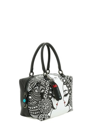 Borsa a mano bianca e nera con volti artistici e motivi floreali, due manici neri e un piccolo portachiavi nero e rosso attaccato.