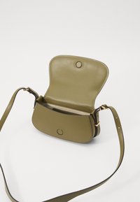 Borsa a tracolla in finta pelle verde oliva, dalla forma arrotondata, con chiusura a scatto magnetico e tracolla regolabile. L'interno presenta una tasca piatta.