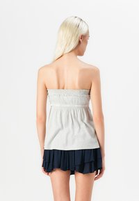 Grijze strapless top met een smock-bustier en een marineblauwe gelaagde rok. Heeft een geplooide textuur en een eenvoudig ontwerp, geschikt voor casual casual wear.