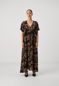 Maxikjole i sort stof med abstrakte sandfargede mønstre, korte flarrende ermer, V-hals og detalj med innsnevret midje, satt sammen med svarte hæler.