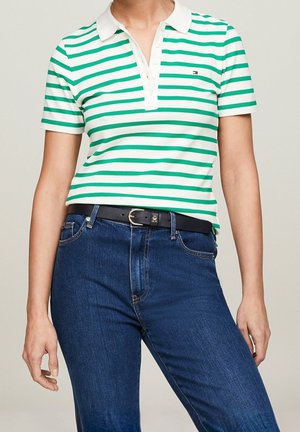 Grön- och vitrandig polotröja med klassisk krage, treknapplås och en liten logotyp på bröstet, i kombination med mörkblå jeans.