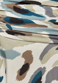 Mehrfarbiger Stoff mit abstrakten Punkten in Teal, Schwarz, Braun und Creme-Tönen, mit glatter Textur und leichtem Glanz, in Lagen gefaltet.