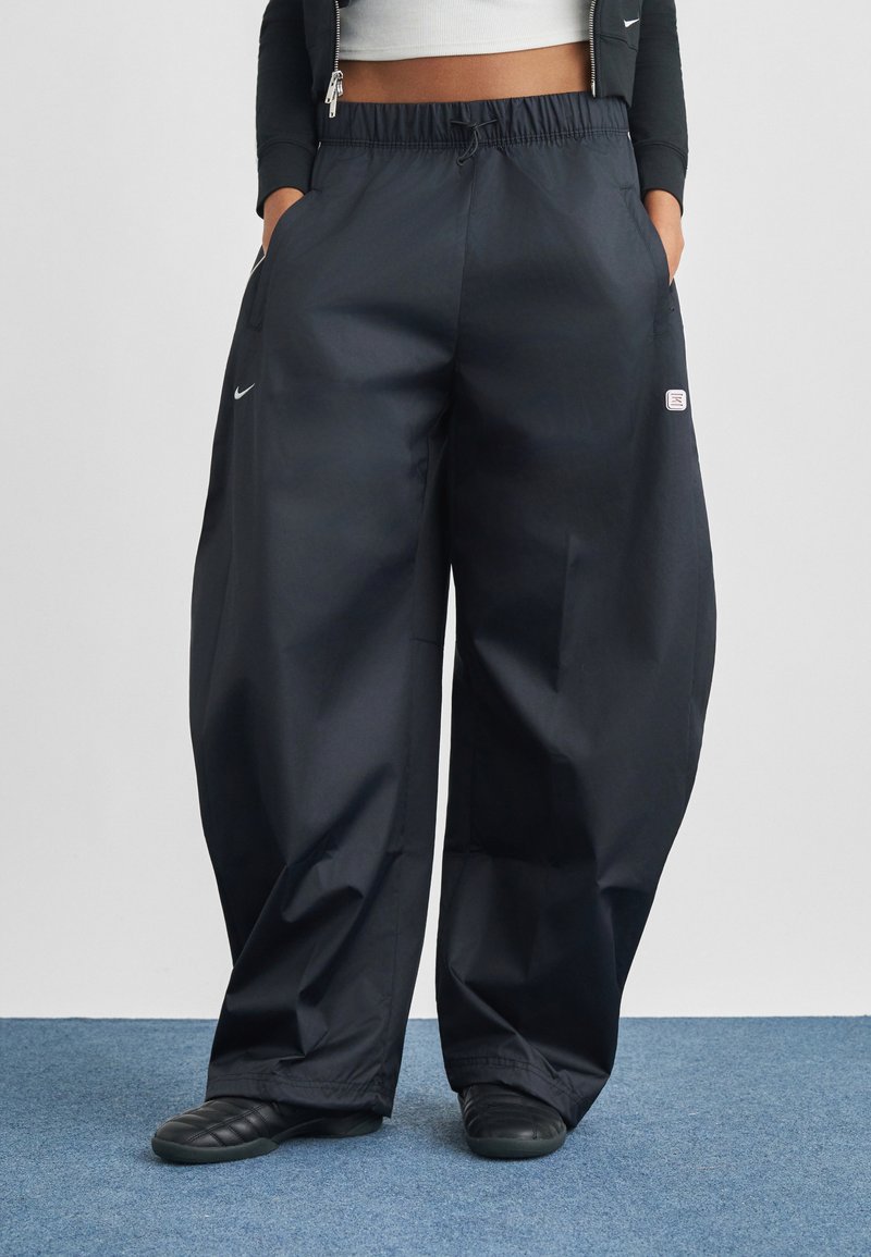 Fekete, bőszárú nadrág könnyű anyagból, elasztikus derékpánttal, oldalzsebekkel és egy kis logóval a bal zseb közelében.