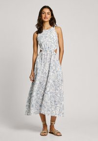 Blommönstrad klänning i vitt och blått, med en figurnära bodice, utstansade sidor och en sväva maxi kjol. I kombination med metalliska sandaler.