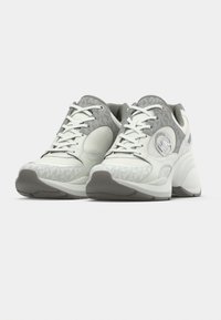 Λευκά και γκρι αθλητικά παπούτσια με υφή στην επάνω επιφάνεια, στρογγυλή μύτη και επενδεδυμένο κολάρο. Διαθέτουν ασημί λογότυπο και χοντρή σόλα.