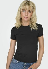 Svart kortärmad t-shirt i slätt material, med rund halsringning och en figurnära design, kombinerad med ljusblå denimjeans.