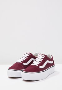 Sneakers in camoscio color bordeaux con dettagli bianchi, caratterizzate da una punta rotonda, lacci piatti e una suola spessa in gomma bianca con una striscia nera.