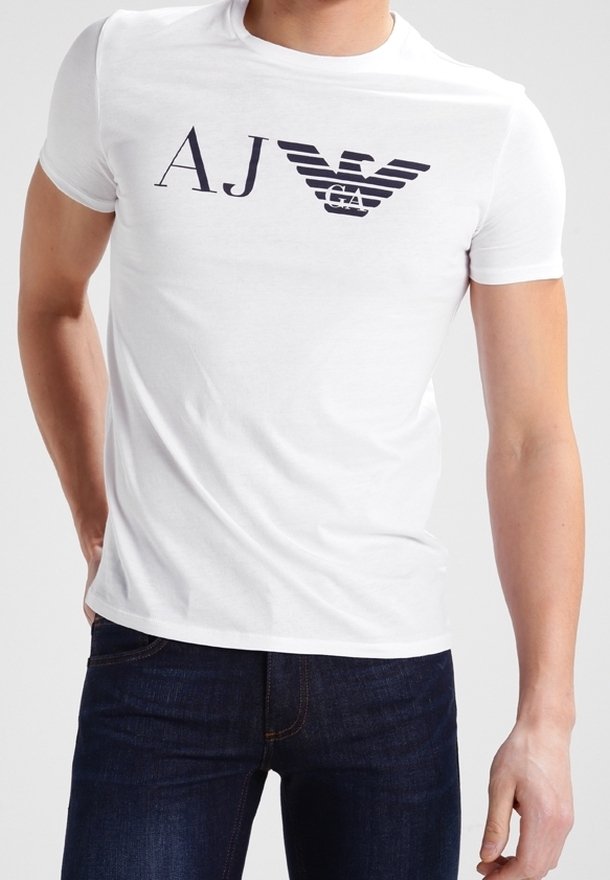 Vit bomulls t-shirt med en svart logotyp som har stiliserade bokstäverna "AJ" och "GA" tillsammans med vingmotiv. Kort ärm och rundad halsringning.