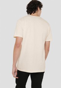 Light beige short-sleeve T-shirt made of cotton. Features a round neck, relaxed fit, and plain back with no visible patterns or accents.