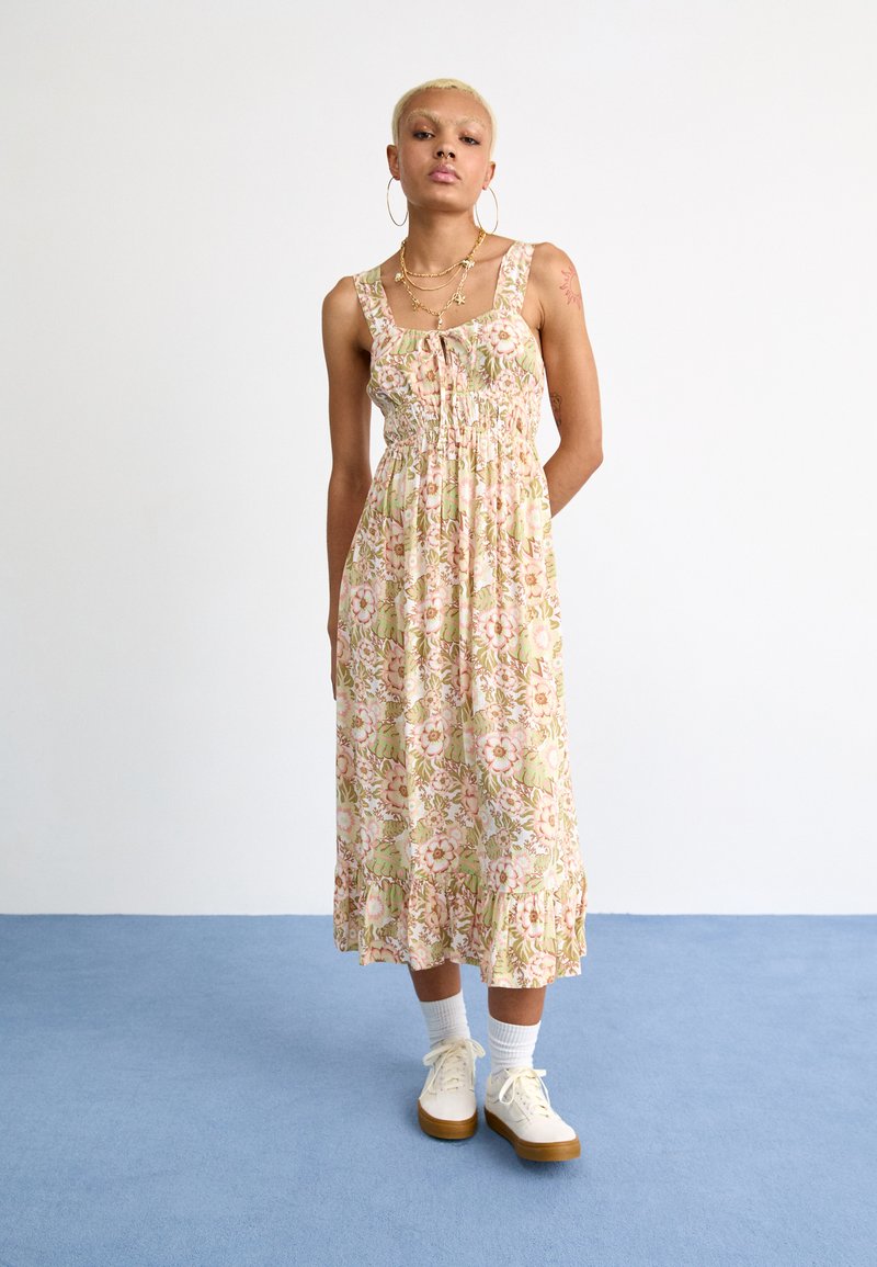 Florale maxi-jurk met een fitted bodice, elastische taille en uitlopende zoom. Lichtroze, groene en crèmekleurige tinten met een geribbelde afwerking aan de onderkant.