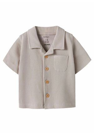 Beigenvärinen, lyhythihainen vohvelineulottu taaperopaita, jossa puiset napit ja pieni rintatasku, varustettu camp-kauluksella.