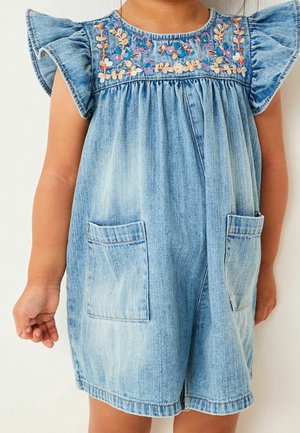 Kleinkind trägt einen hellblauen Jeans-Einteiler mit Rüschenärmel, aufgesetzten Taschen vorne und Blumenstickerei auf der Brust.