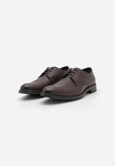 Chaussures habillées en cuir marron avec une finition lisse, bout rond et fines lacets. Les semelles sont légèrement surélevées pour un confort supplémentaire.