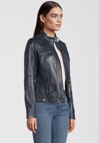 Marineblauwe leren jas met een staande kraag, rits aan de voorkant en meerdere ritszakken; getailleerd ontwerp met subtiele stikdetails.