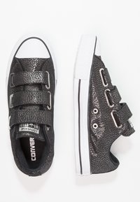 Czarne teksturowane sneakersy z trzema regulowanymi paskami na rzep, białym gumowym noskiem i podeszwą, wyposażone w srebrne okucia oraz czarne boczne akcenty.