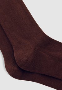 Brune bomuldsstrømper med ribbet tekstur, der har et sømløst tådesign og en glat ankelmanchet. Materialet ser blødt og slidstærkt ud.