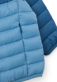 Giacca leggera tipo puffer in due tonalità di blu, con texture trapuntata, tasca con zip e orlo a coste.