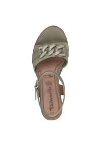 Sandale en suede verte avec une bride tressée, bout ouvert et une fine sangle à la cheville. Présente une semelle intérieure marron avec le nom de la marque embossé.