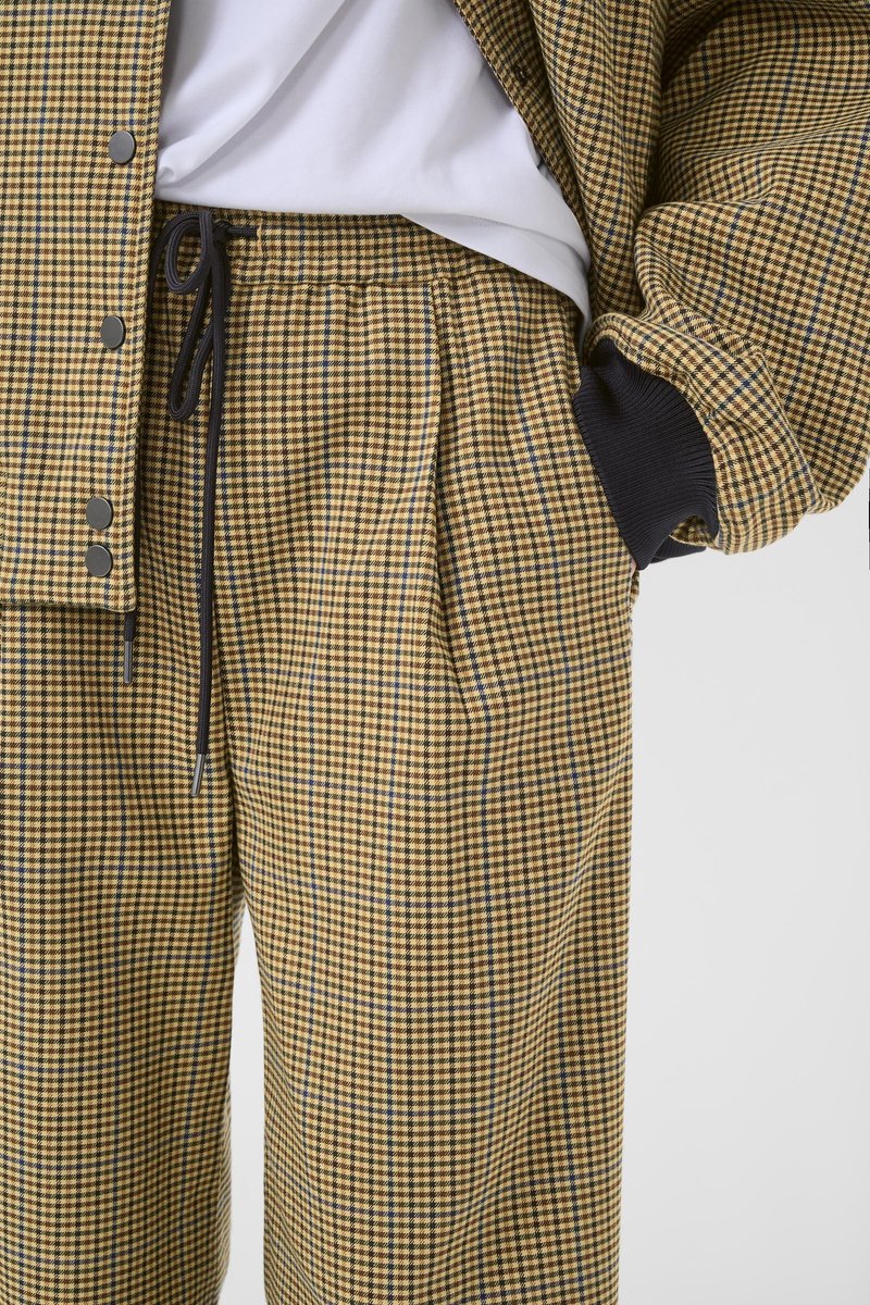 Plaid jacket and pants set in yellow and black with blue accents. Features a drawstring waistband and large front pockets. Soft fabric texture.