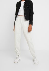 Svart denimjacka, vit beskuren t-shirt, ljusgrå mjukisbyxor, vita högkantsneakers. Outfit har en avslappnad passform och ribbade muddarna.