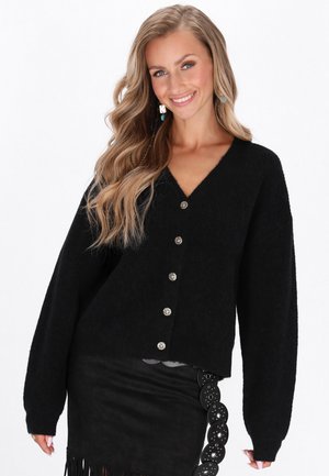 Black knitted cardigan with a V-neck, oversized sleeves, and front button closure. Silver buttons add detail to the textured fabric.