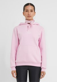 Sweat à capuche rose en molleton, avec une poche frontale, un cordon de serrage ajustable et un logo brodé sur la poitrine.
