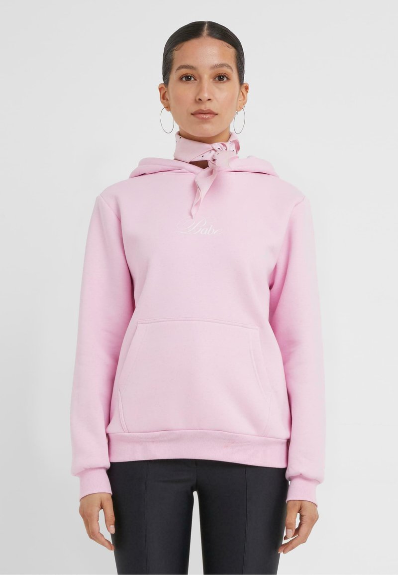 Sweat à capuche rose en molleton, avec une poche frontale, un cordon de serrage ajustable et un logo brodé sur la poitrine.
