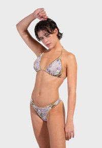 Trokutasti bikini u uzorku leopard kože s cvjetnim detaljima. Ima zlatne remene i donji dio s niskim strukom, izrađen od glatkog materijala.