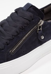 Baskets en daim bleu marine avec larges lacets en tissu, fermeture éclair latérale en métal et semelle blanche en caoutchouc avec gravure de la marque.