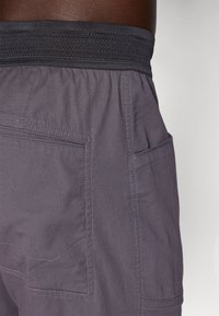 Γκρι σορτς από ελαφρύ ύφασμα με υφασμάτινη μαύρη ελαστική μέση, που διαθέτει δύο πλαϊνές τσέπες και αντίθετη ραφή.