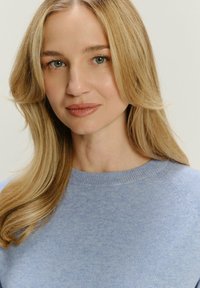 Jasnoniebieski sweter wykonany z miękkiego materiału, z okrągłym dekoltem, z delikatnymi prążkowymi akcentami na kołnierzu i rękawach.