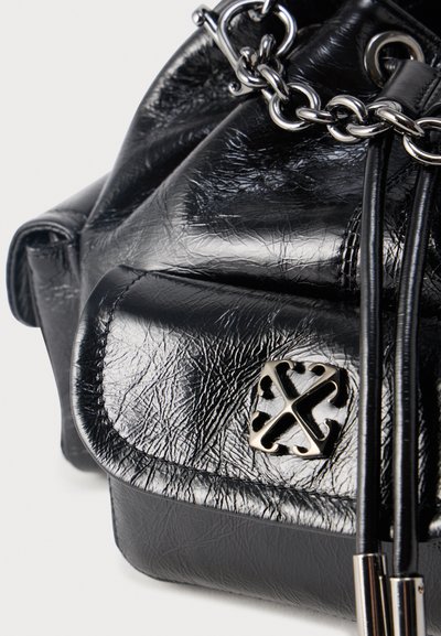 Μαύρη τσάντα χειρός από δερμάτινη υφή με αλυσίδα ασημί λουρί, διακοσμητικό μεταλλικό έμβλημα και κλείσιμο με κορδόνι και μεταλλικά άκρα.