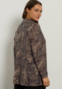 Blusa a maniche lunghe con un design a stampa animale marrone e beige, caratterizzata da un colletto rotondo, taglio diritto e tessuto leggero.
