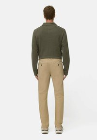 Green long-sleeve shirt with a collar, paired with beige trousers. The shirt has a textured finish; trousers include two back pockets.