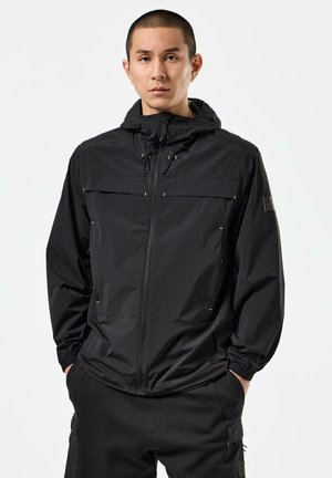 Schwarze leichte Jacke mit Reißverschluss vorne, verstellbare Kapuze und zwei Fronttaschen. Merkmale sind elastische Bündchen und dezente gelbe Akzente.