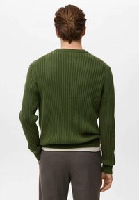 Zelený rebrovaný sveter s dlhými rukávmi, okrúhlym výstrihom a textúrovaným povrchom, vrstvený cez svetlú košeľu.