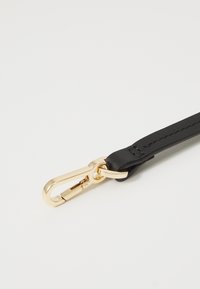 Cinturino in pelle nera con hardware in metallo dorato; presenta una texture liscia e dettagli di cuciture a contrasto.