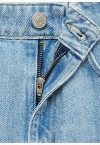 Jean en denim bleu clair avec une fermeture éclair métallique partiellement ouverte et un bouton métallique au-dessus de la fermeture éclair.