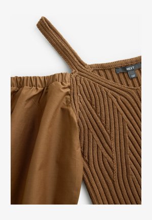 Rudas nėrinių viršus su tekstūruotu dizainu ir plačia petneša, derinamas su lygiu, surinktu liemeniu iš atitinkamos rudos medžiagos.