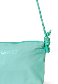 Een turkooise tas met een gladde, glanzende textuur, voorzien van een geknoopt touwhengsel en het "DAY ET"-logo in reflecterend zilver.