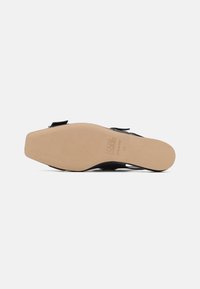 Podplatka črne usnjene sandale s kvadratnim prstom, s tiskanim napisom "KARL LAGERFELD Made in Italy 37", prikazana na beli podlagi.