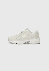 Baskets de sport blanches en maille avec un dessus texturé, un design élégant et une semelle rembourrée avec des accents gris et des détails de marque.