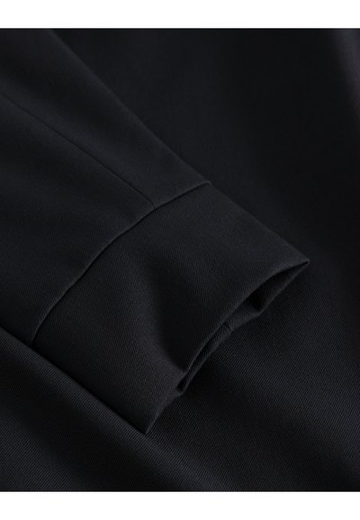 Manchon en tissu noir avec une texture tissée lisse et un bord replié. Le design présente une apparence soignée et bien ajustée.