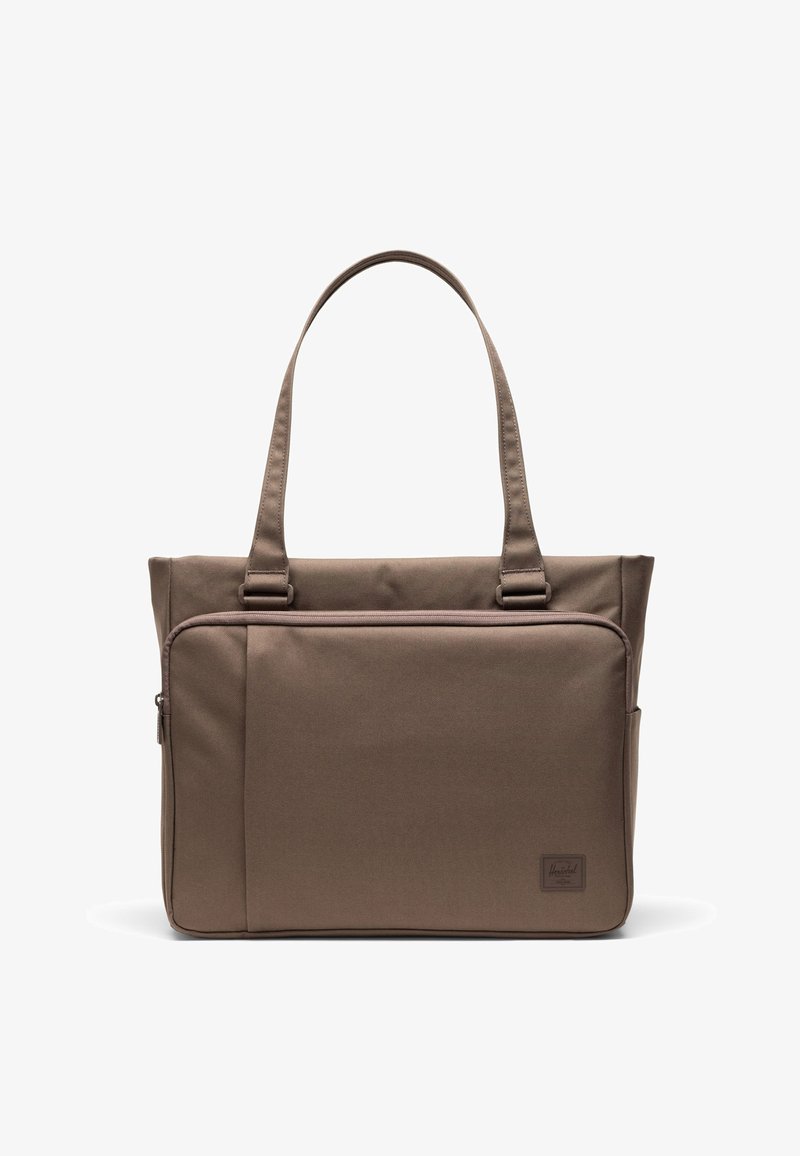 Sac cabas marron avec deux anses, grande poche zippée à l'avant, design simple et petit logo de la marque dans le coin inférieur.