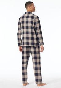 Set di pigiama a quadri in navy, beige e grigio. Maglia a maniche lunghe e pantaloni larghi con motivo a quadri abbinato. Tessuto morbido, vestibilità comoda.