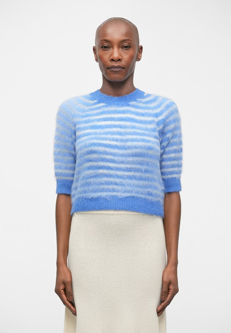 Sweater cropped às riscas azuis com mangas curtas, feito de um material suave e felpudo. Apresenta riscas azuis claras e escuras num padrão em gradiente.