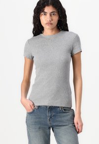 Tricou gri cu mânecă scurtă, cu un design ajustat, realizat dintr-un material diferit. Stil casual, asortat cu blugi albaștri, punând în evidență un aspect simplu.