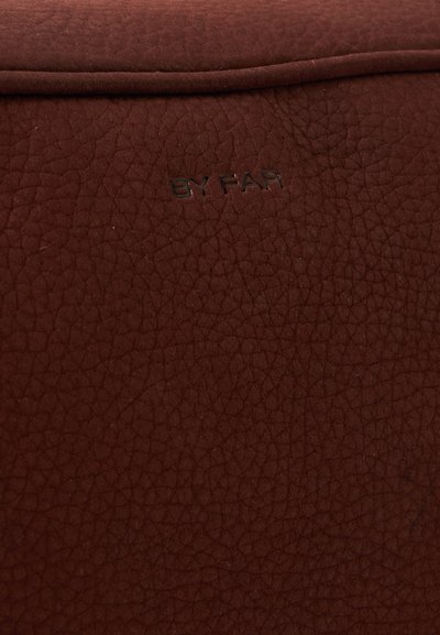 Surface en cuir marron texturée avec un texte noir en relief indiquant "BY FAR" près du centre supérieur.