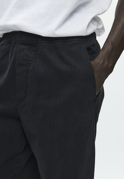 Pantalon de jogging noir avec une ceinture élastique. Confectionné dans un tissu doux et texturé, doté de poches latérales et d'une coupe droite.